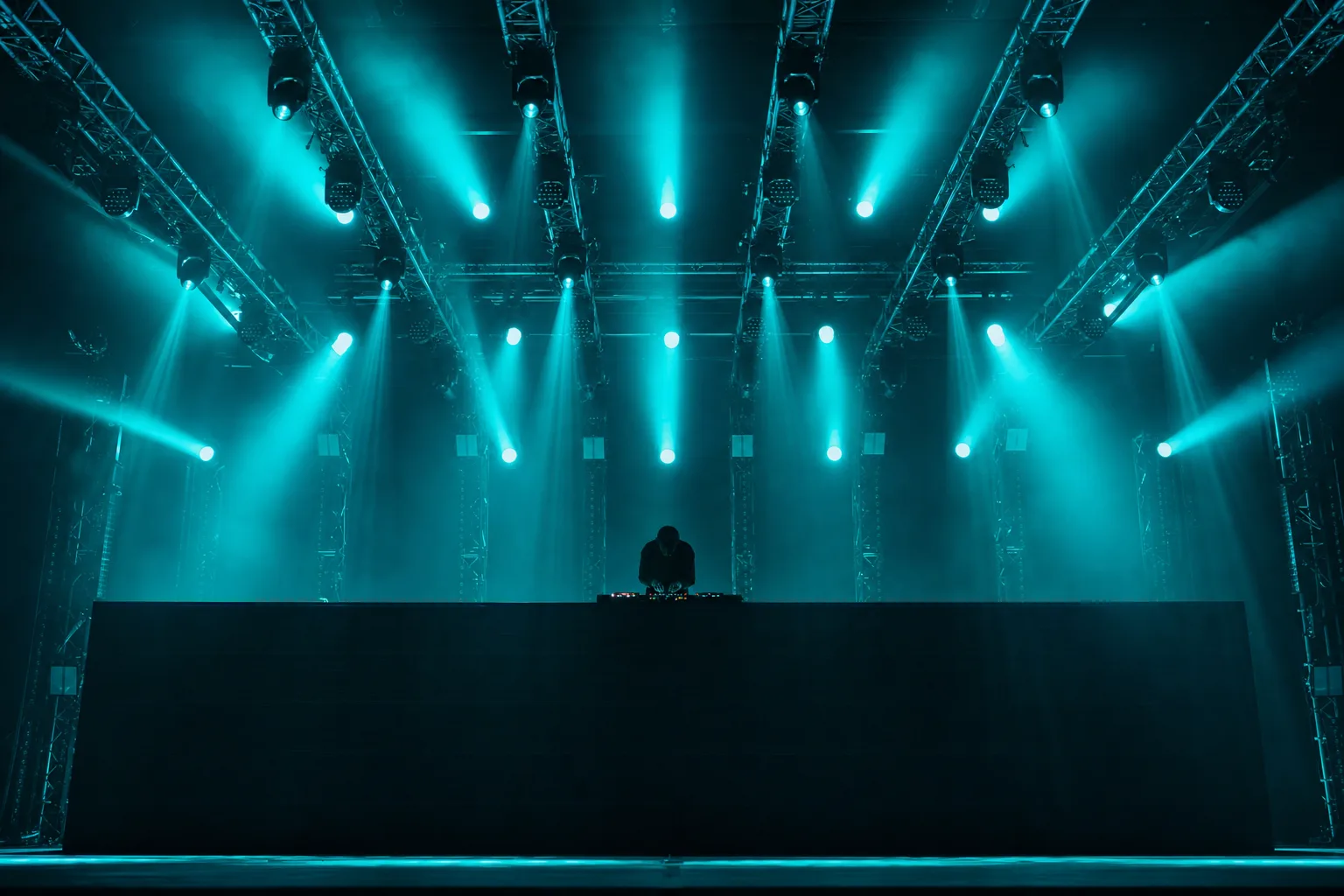 El foso frente a la cabina, con el truss encima y las manos del disc jockey sobre la consola
