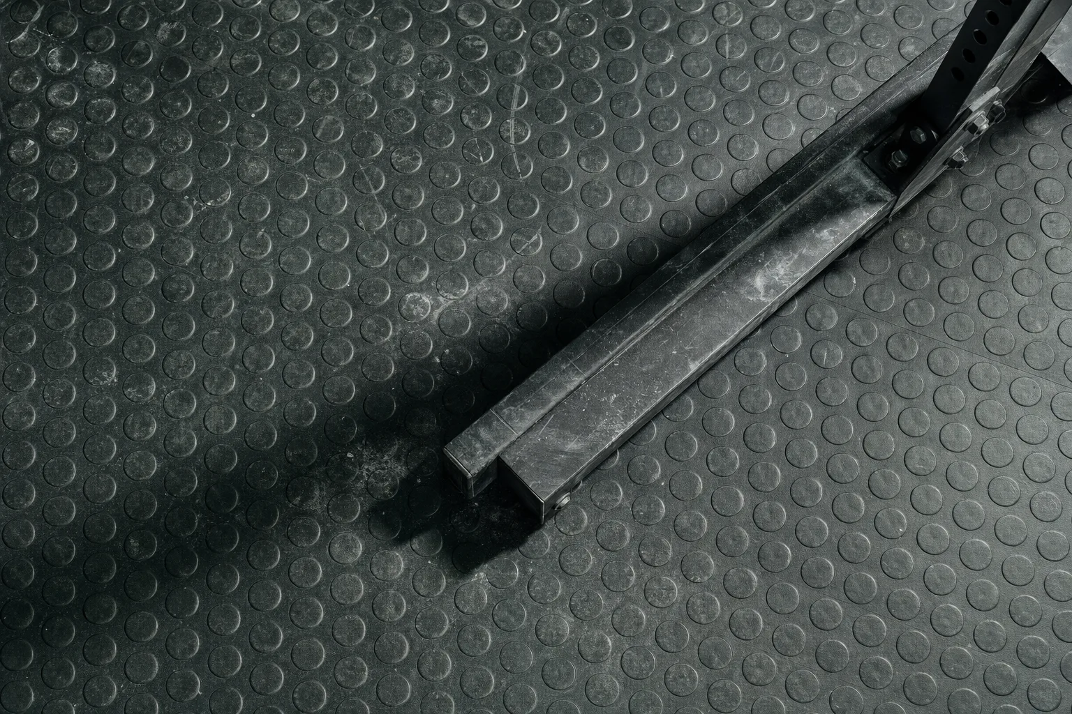 Piso de goma de sala de musculación visto desde arriba, con marcas de uso