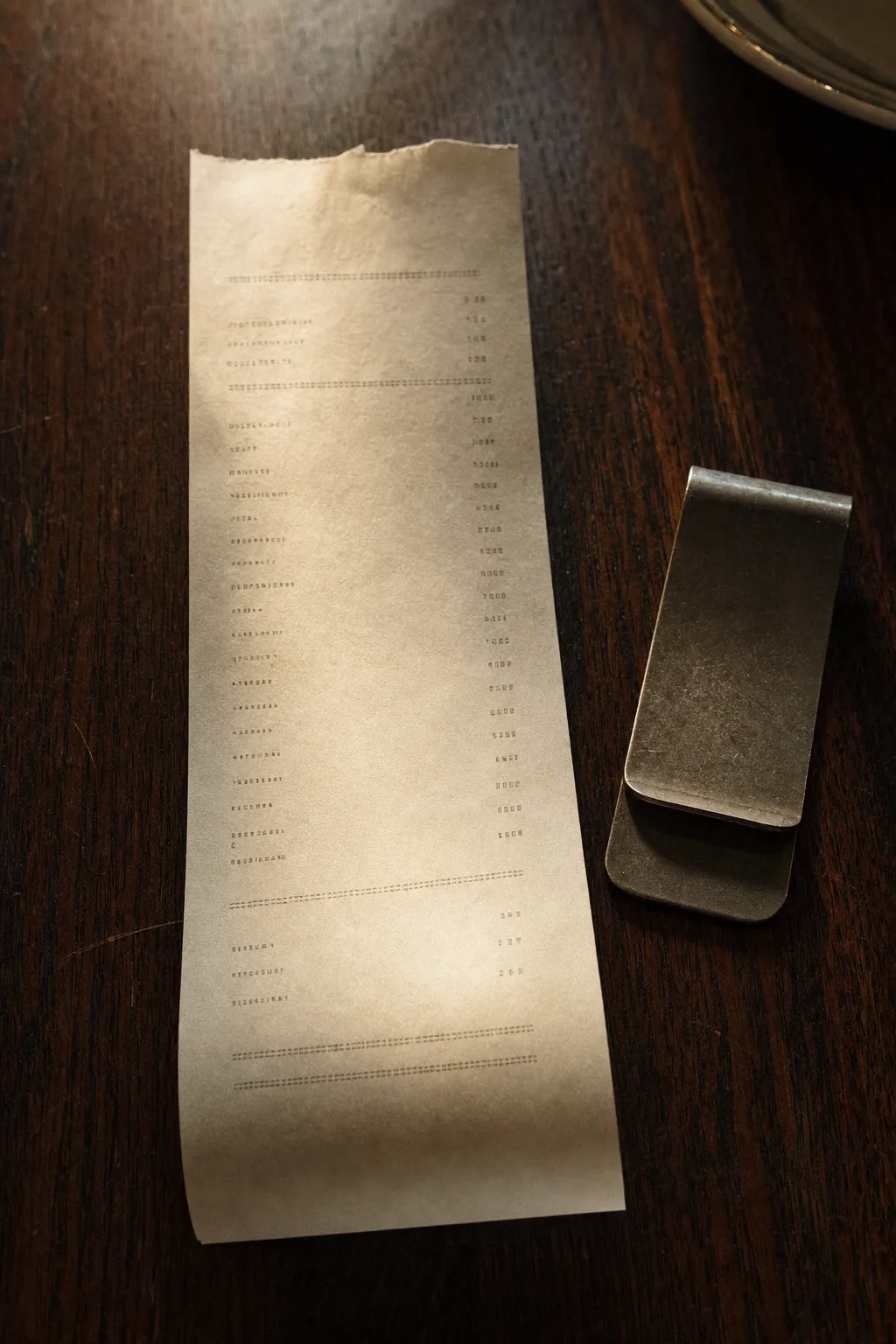 Ticket de impresora térmica sobre una mesa de madera oscura, con el borde superior cortado a mano