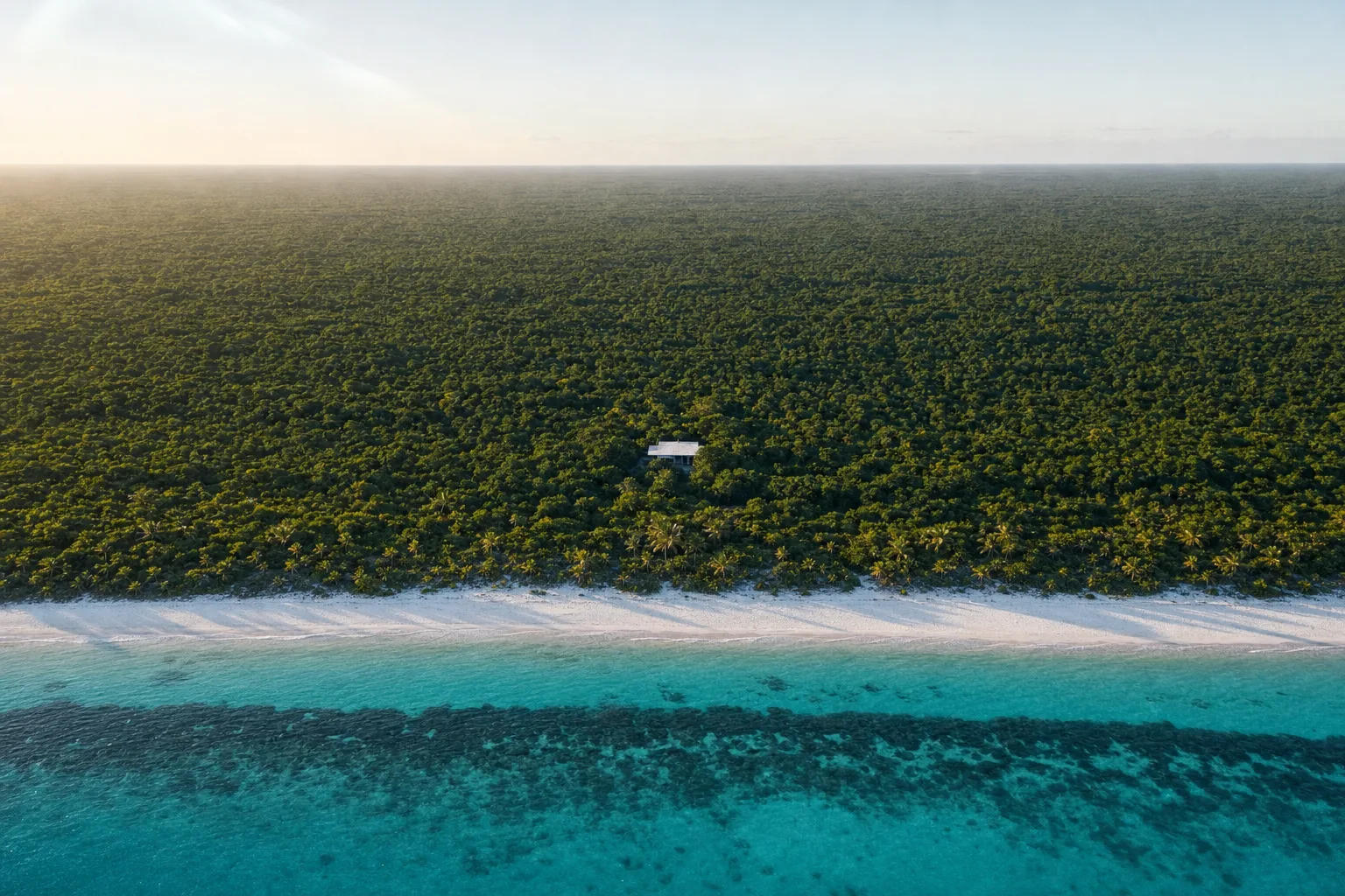 La costa de Tulum desde el aire, con la línea del arrecife y la selva llegando hasta la arena
